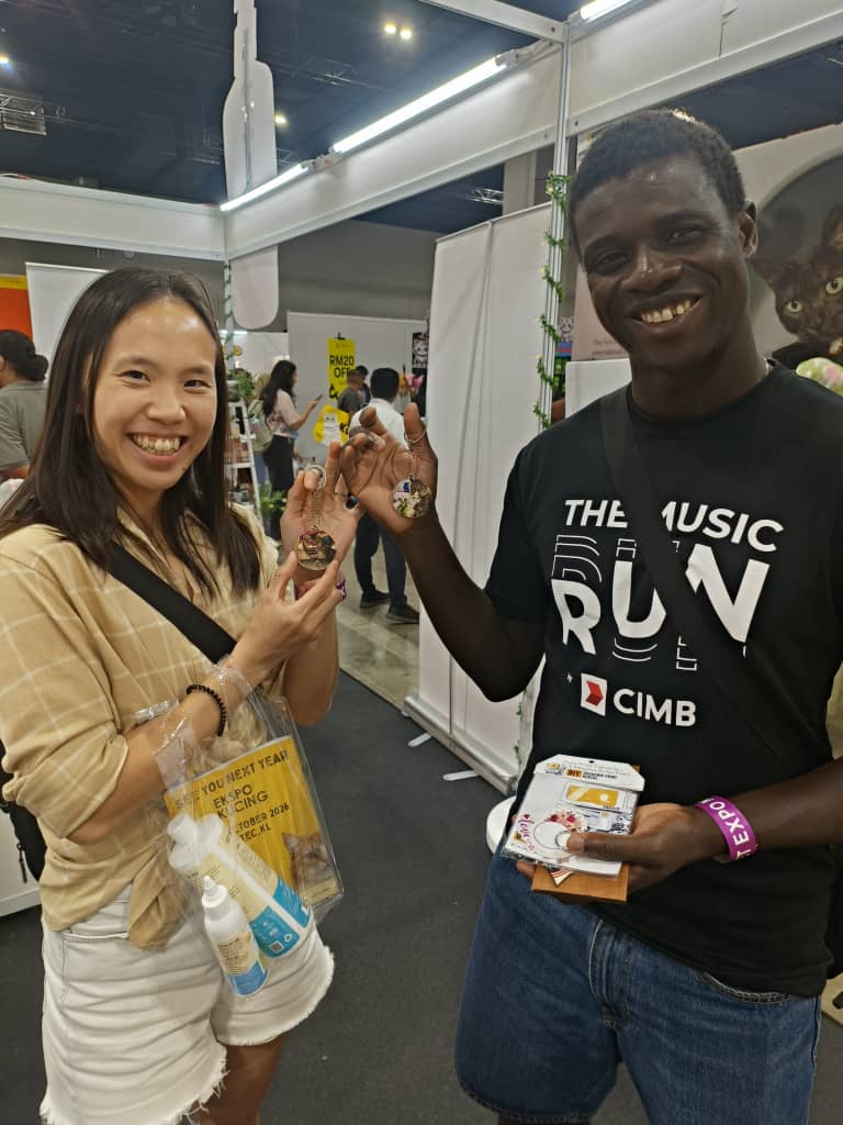 Two visitors holding up custom keychains printed at the Magix booth